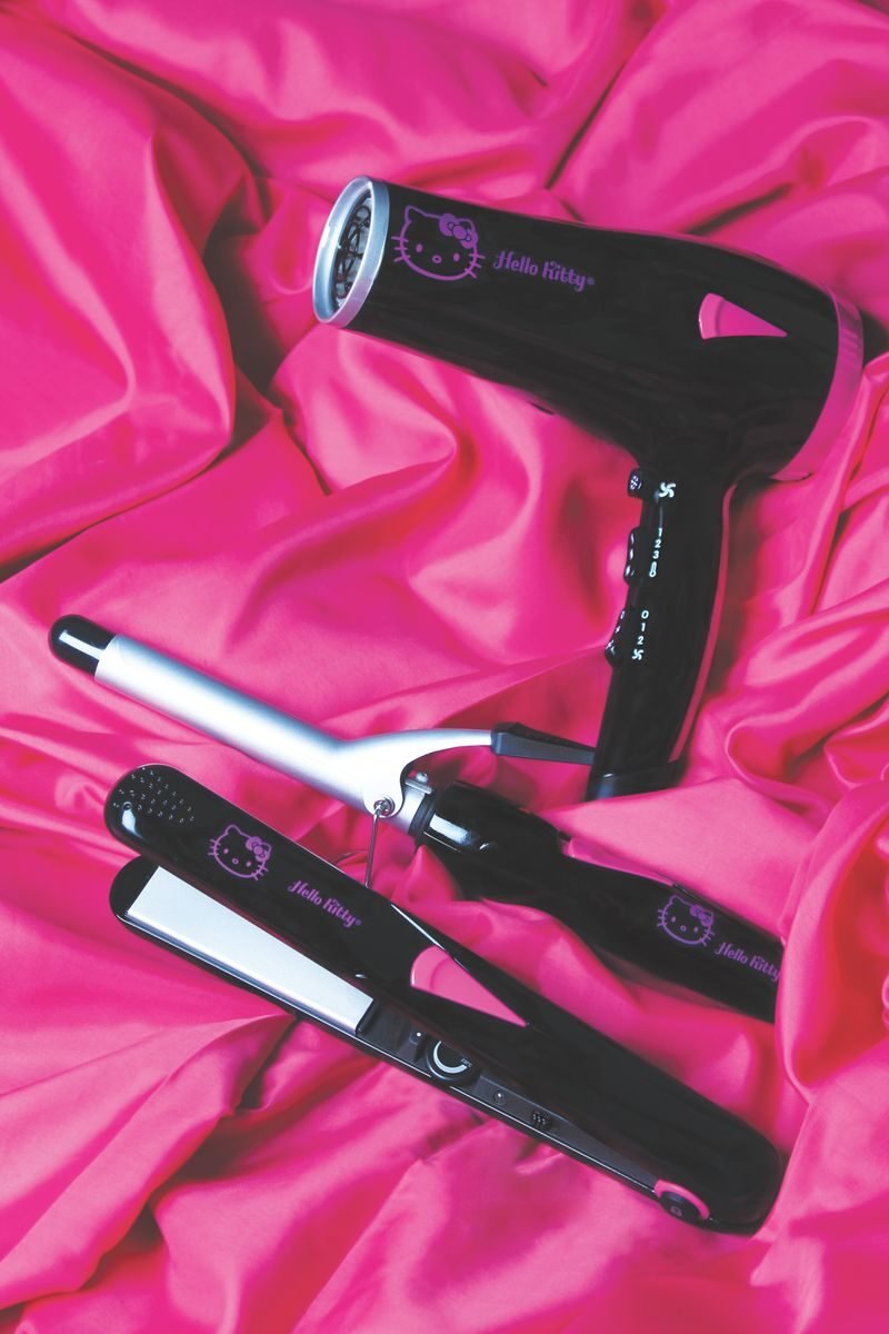 Set of Hello Kitty-themed hair styling tools on vibrant pink fabric, ideal for beauty enthusiasts.