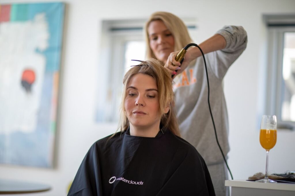 A woman gets her hair styled with a curling iron in a contemporary salon setting.